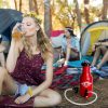 Woman drinking a beverage from a Growlveller pressurized growler at a camp site.