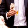 gentleman in a suit holding a 1oz shot glass.