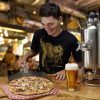 Man serving pizza along with a 1 gallon unitank growler from Craft Master Growlers.