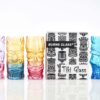 set of 4 multicolored Tiki glasses on white background next to packaging.