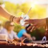 a hand, handing a glass of sparkling water to another hand.