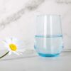 blue Italian style 13oz tumbler glass on a table with a daisy.