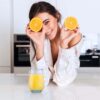 girl holding orange halves with a glass of OJ in a 13oz blue tumbler.