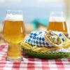 set of 2 footed baloon style IPA glasses on a table setting with a gyro sandwich and fries.