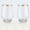 two gold rimmed 18oz stemless wine glasses on a white background.
