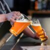 wheat beer being poured from a pitcher into a 24 oz jumbo pilsner glass.