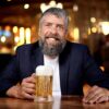 gentleman sitting at a bar top with a frothy beer in a 16oz German inspired beer stein.