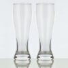 Two American pint 17oz pilsner glasses on a white background.