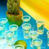 tequila shooters on a blue table with salted rims in 1.75 oz flared shot glasses.