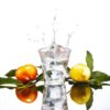 splash of water in 10oz handblown white rocks glass, set next to an orange and a lemon.