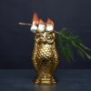 a copper owl tiki mug with a branch over it and burning marshmallows.