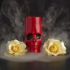 cool picture of a 12oz ceramic red skull tiki glass between two yellow roses with mist.