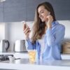 woman looking at phone with an orange beverage in a 10oz white handblown rocks glass.