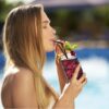 woman drinking grape juice from a 20 oz highball tiki glass